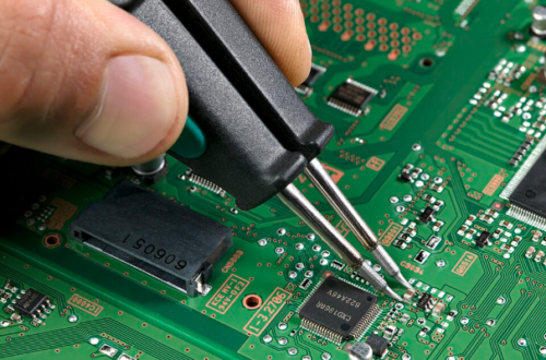 PCB 위에서 핀셋으로 SMD 부품을 납땜하는 근접 사진, 초록색 회로기판과 정밀 인두 팁이 보이는 모습